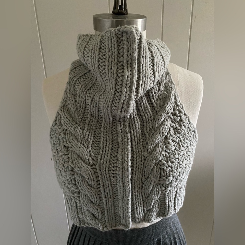 Cable knit vest with hidden snap tape placket.